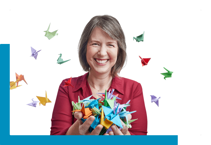 Woman smiling holding and surrounded by colorful origami 