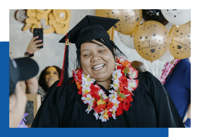 Student smiling and celebrating at their graduation with balloons