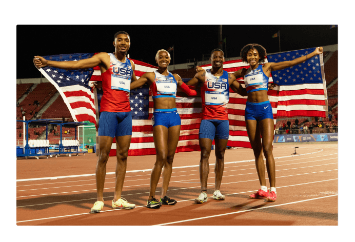 Four athletes smiling, draped in the American flag 